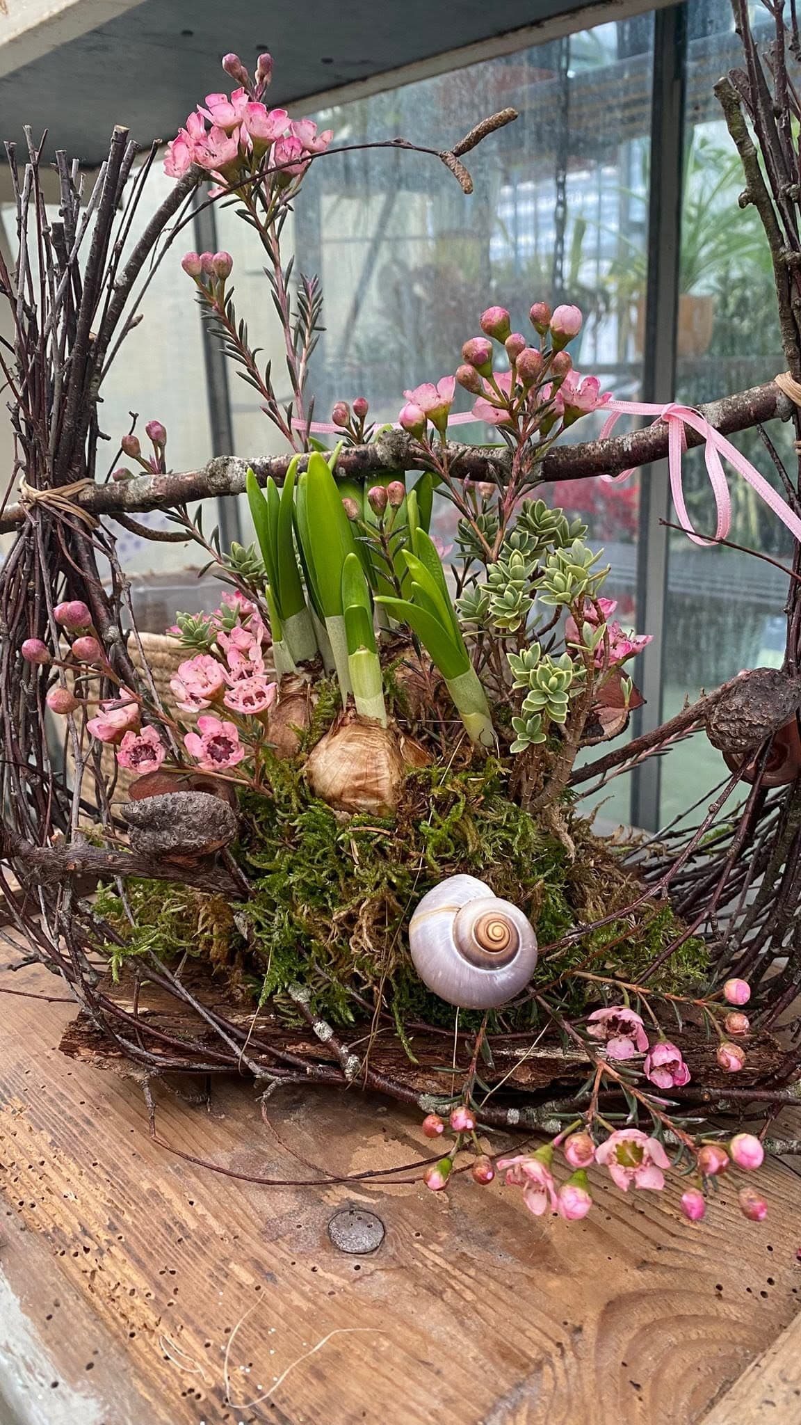 Frühlingsgesteck aus Zweigen mit Hyazinthenzwiebeln und Wachsblumen