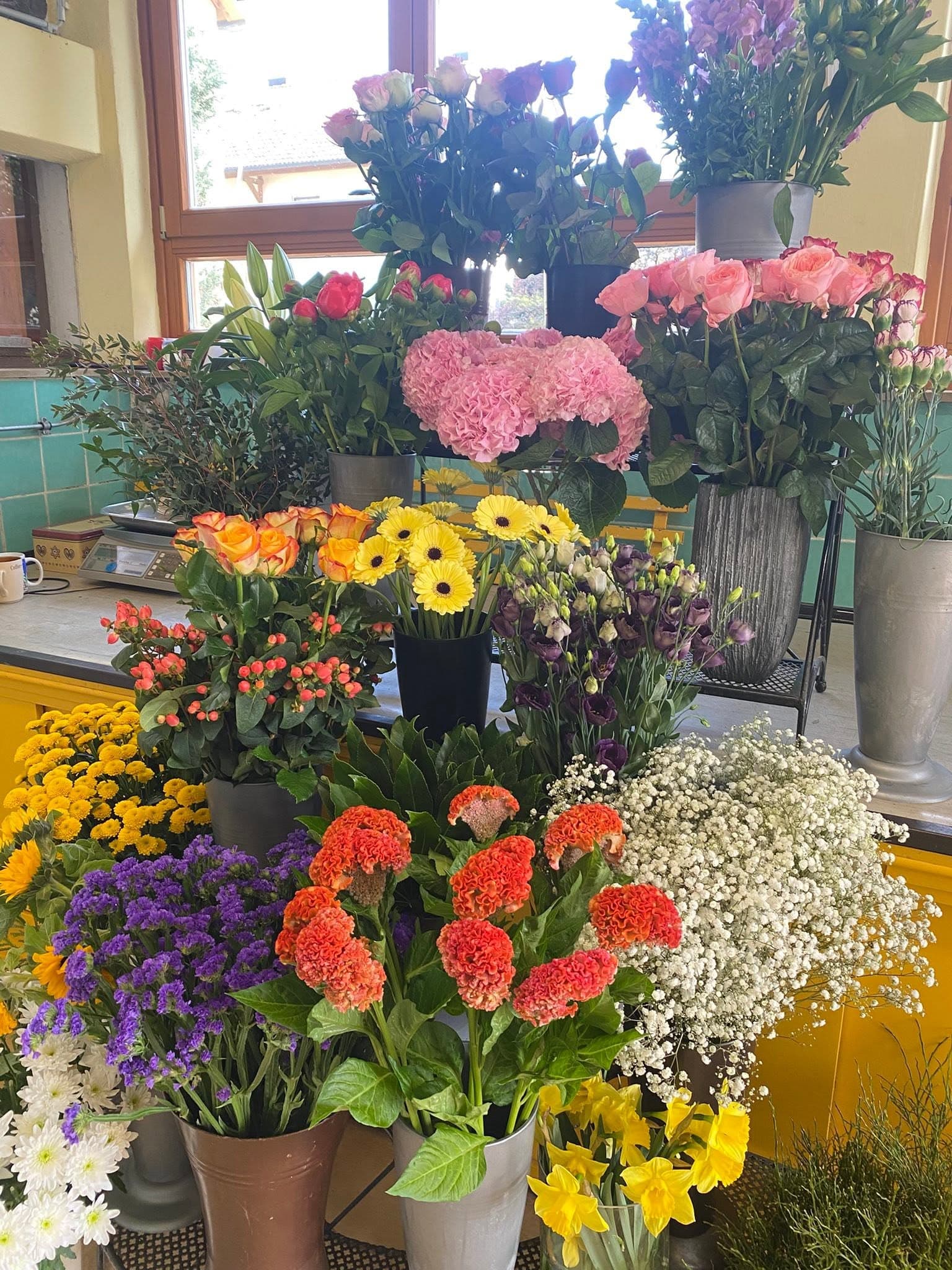 Reich gefüllte Schnittblumenauslage mit Rosen, Gerbera und Hortensien am Fenster