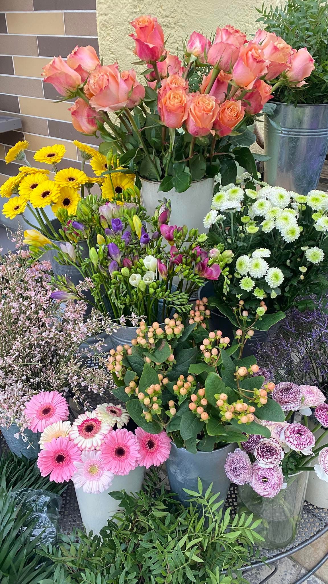 Blumenauslage in Eimern vor dem Laden mit Rosen, Gerbera und Freesien