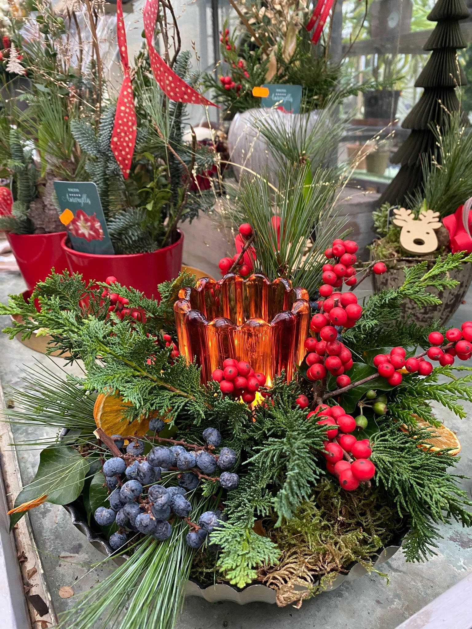 Weihnachtliches Tischgesteck mit Windlicht, Ilex-Beeren und Koniferengrün